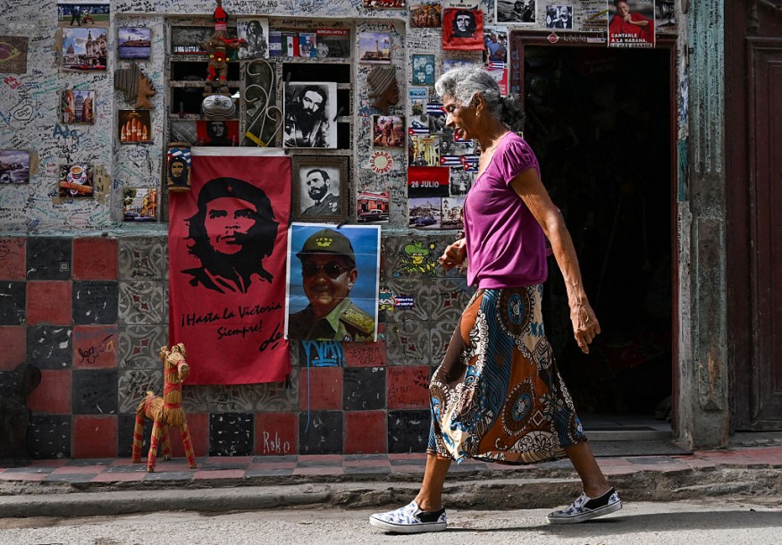 An elderly woman walks in a street of Havana